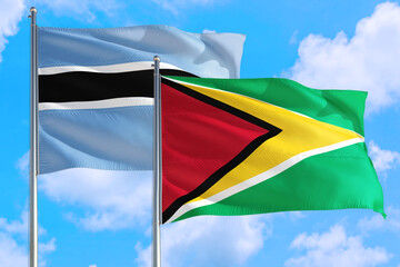 Guyana and Botswana national flag waving in the windy deep blue sky. Diplomacy and international relations concept.