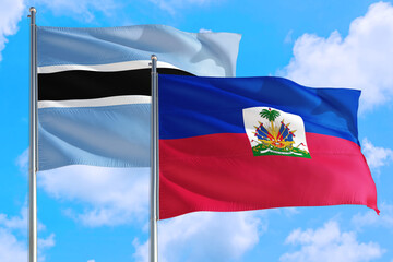 Haiti and Botswana national flag waving in the windy deep blue sky. Diplomacy and international relations concept.