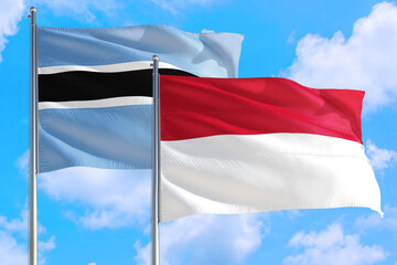 Indonesia and Botswana national flag waving in the windy deep blue sky. Diplomacy and international relations concept.