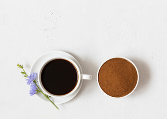 Obraz na płótnie Canvas Cup with chicory drink and chicory powder on a white background close-up. Natural healthy coffee substitute. Copy space, top view
