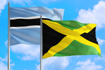 Jamaica and Botswana national flag waving in the windy deep blue sky. Diplomacy and international relations concept.