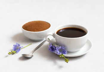Chicory drink, chicory powder and blue flowers on a white background close-up. Alternative to coffee. Side view.