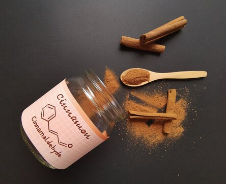 Cinnamon sticks and milled cinnamon spice in the glass jar with structural chemical formula of cinnamaldehyde (the major component of cinnamon). Winter spice, cinnamon sticks and cinnamon powder.