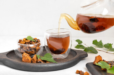 Chaga mushroom drink in a glass cup and teapot on a white background. Useful chaga tea to boost immunity.