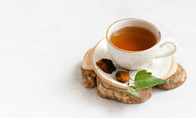 Chaga tea in a white cup on a white background. Infusion of birch mushroom. Trendy healthy drink. Copy space.