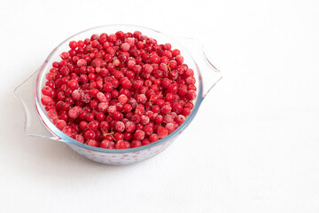 Frozen red currant on a white background. Red frozen berries in a bowl. Healthy diet. Space for...