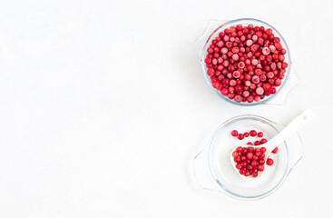 Frozen cranberry berries in a transparent bowl on a white background. Healthy food concept. Copy space, top view.