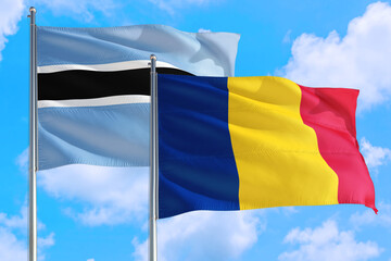 Romania and Botswana national flag waving in the windy deep blue sky. Diplomacy and international relations concept.