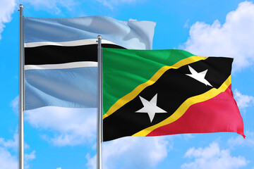 Saint Kitts And Nevis and Botswana national flag waving in the windy deep blue sky. Diplomacy and international relations concept.