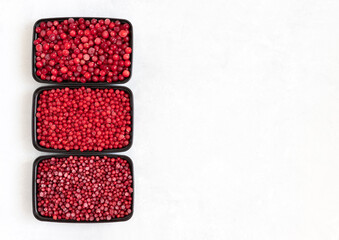 Containers with frozen berries mix on a white background. Storage of frozen food. Cranberries, red currants, lingonberries. Copy space. Top view, flat lay.