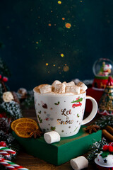 Christmas or New Year festive card with coffee cup with fir branches, sweets and snowball. Hot chocolate with marshmallow and cinnamon. Christmas background with bokeh.