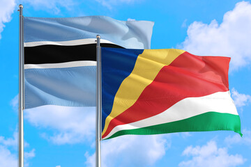 Seychelles and Botswana national flag waving in the windy deep blue sky. Diplomacy and international relations concept.