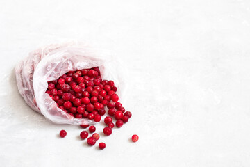Frozen cranberries in a plastic bag on a white background. Frozen red berries food. Stocks concept. Copy space.