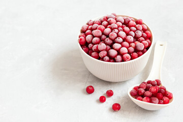 Frozen red berries in a bowl with a spoon on a white background. Frozen cranberries. Vitamins. Copy space.