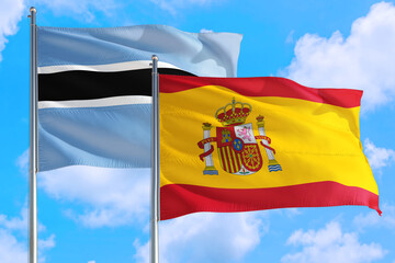 Spain and Botswana national flag waving in the windy deep blue sky. Diplomacy and international relations concept.