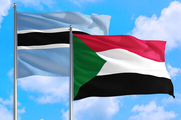 Sudan and Botswana national flag waving in the windy deep blue sky. Diplomacy and international relations concept.
