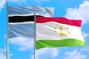 Tajikistan and Botswana national flag waving in the windy deep blue sky. Diplomacy and international relations concept.