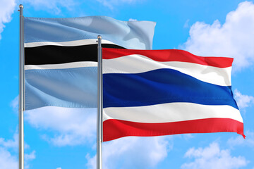 Thailand and Botswana national flag waving in the windy deep blue sky. Diplomacy and international relations concept.