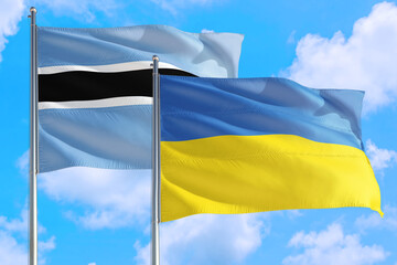 Ukraine and Botswana national flag waving in the windy deep blue sky. Diplomacy and international relations concept.