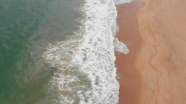 Aerial drone shot view the ocean of the ocean waves, beautiful waves do not end frames one by one while the turquoise sea waves break on the sandy coast. 4K