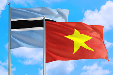 Vietnam and Botswana national flag waving in the windy deep blue sky. Diplomacy and international relations concept.