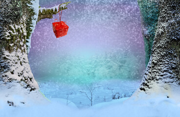 Red gift box in snowfall hanging on snowy branch. New Year fairy tale forest background. Winter landscape