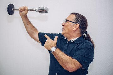 an adult man picks up an announcer's microphone and pretends to sing with his arm raised