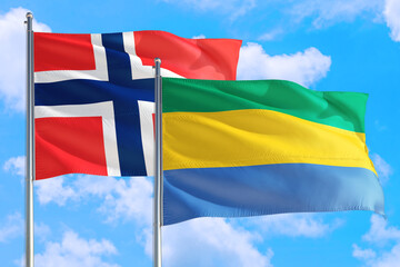 Gabon and Bouvet Islands national flag waving in the windy deep blue sky. Diplomacy and international relations concept.