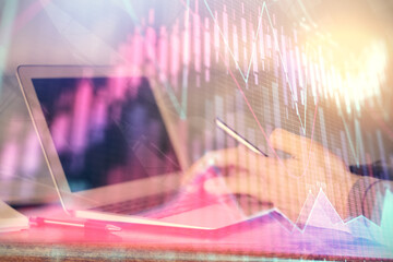 Double exposure of man's hands holding and using a digital device and forex graph drawing....