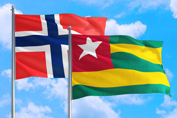 Togo and Bouvet Islands national flag waving in the windy deep blue sky. Diplomacy and international relations concept.
