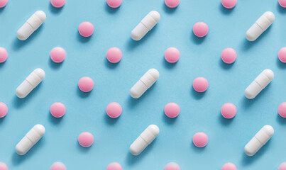 Scattered Pills on a blue background , Medicine concept. Multiple long and round white capsue and...