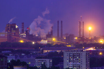 View of the evening industrial city, a large factory and the river