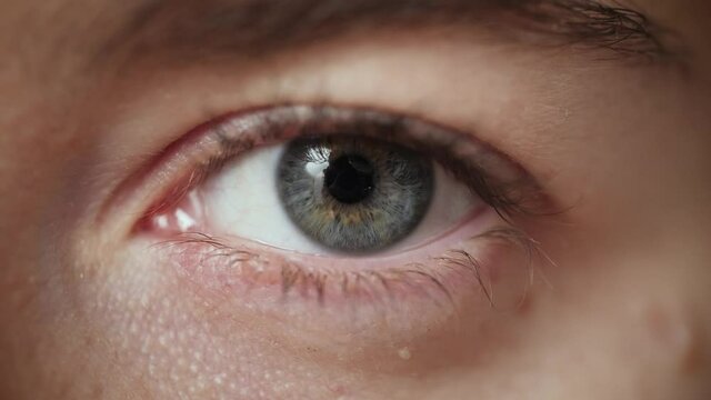 Extreme close up of Woman opening beautiful eye with blue iris. Attractive girl, a young female model with natural make-up and long eyelashes looking at camera. Slow-motion, macro, 4K.