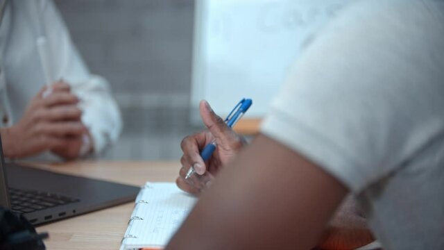 A woman and black man having an english lesson - man holding a pen and about to make notes