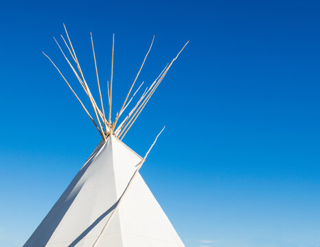 a Native American tipi under bright blue skies with copy space