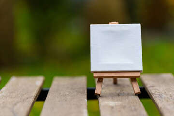 Closeup of a tiny canvas with space for text on a stand on a wooden surface