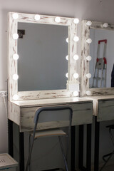 A chair sitting in front of a mirror. Dressing room.