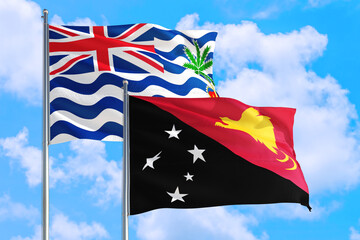 Papua New Guinea and British Indian Ocean Territory national flag waving in blue sky. Diplomacy and international relations concept.