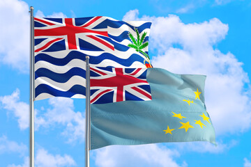 Tuvalu and British Indian Ocean Territory national flag waving in blue sky. Diplomacy and international relations concept.