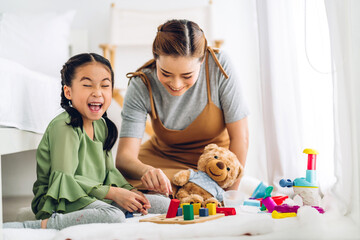 Portrait of enjoy happy love asian family mother and little asian girl smiling playing with toy build wooden blocks board game in moments good time at home