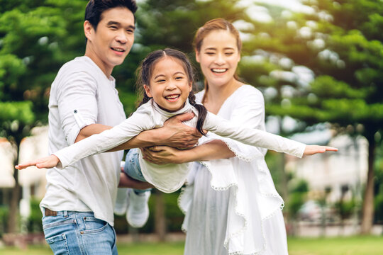 Portrait of enjoy happy love asian family father and mother  holding little asian girl smiling playing and having fun moments good time in summer park at home