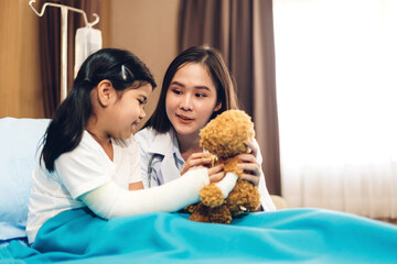 Asian smiling woman doctor service help support discussing and consulting talk to little girl patient give teddy bear and check up information in hospital