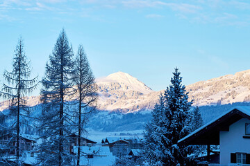 Fototapeta premium Old Austrian village on the snowy slope in the shadow of the mountains. Ski and leisure activity travel destinations