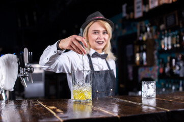 Girl barman makes a cocktail at the taproom