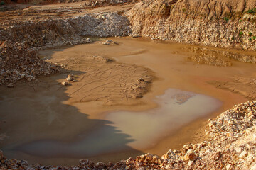 A puddle of mud at the bottom of a limestone quarry
