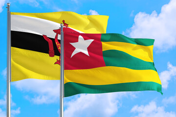 Togo and Brunei national flag waving in the windy deep blue sky. Diplomacy and international relations concept.