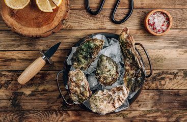 Fresh oysters with ice and lemon on a rustic wooden background.