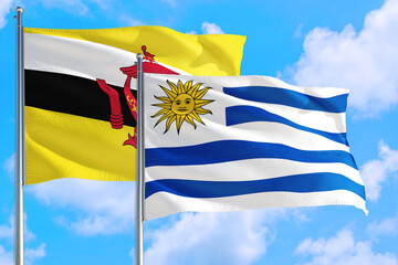 Uruguay and Brunei national flag waving in the windy deep blue sky. Diplomacy and international relations concept.