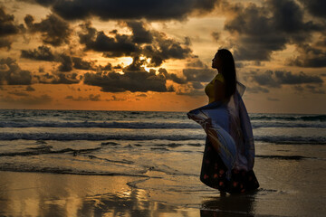 Happy women Stand and admire the sunset over the sea at dusk, holding a thin cloth in your hand.