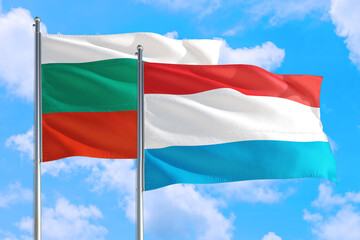 Luxembourg and Bulgaria national flag waving in the windy deep blue sky. Diplomacy and international relations concept.